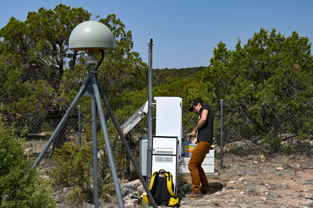 man lifts battery into GPS station enclosure