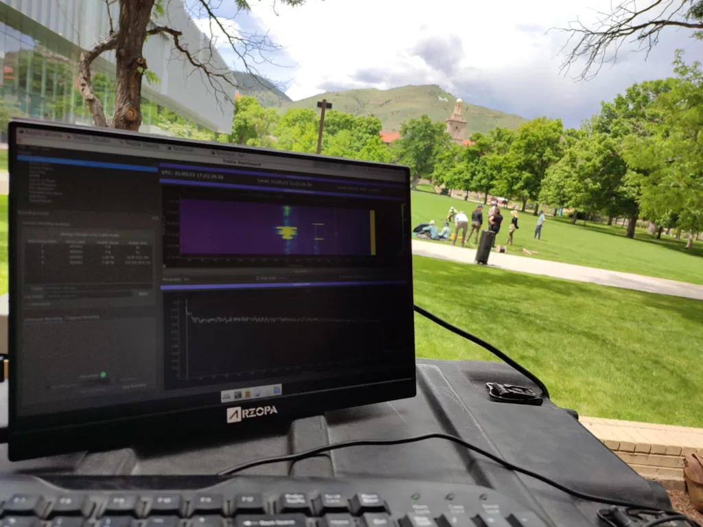 computer screen with people in grass college quad in background