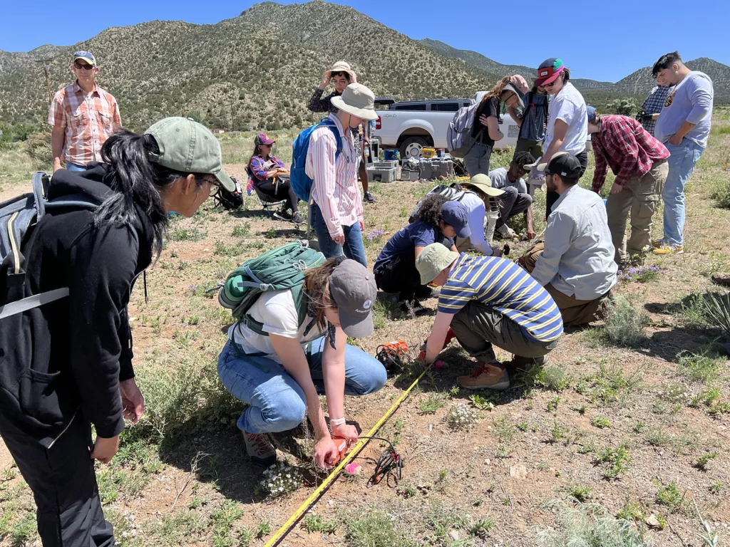 Students installing orange geophone sensors every meter along a North-South array.