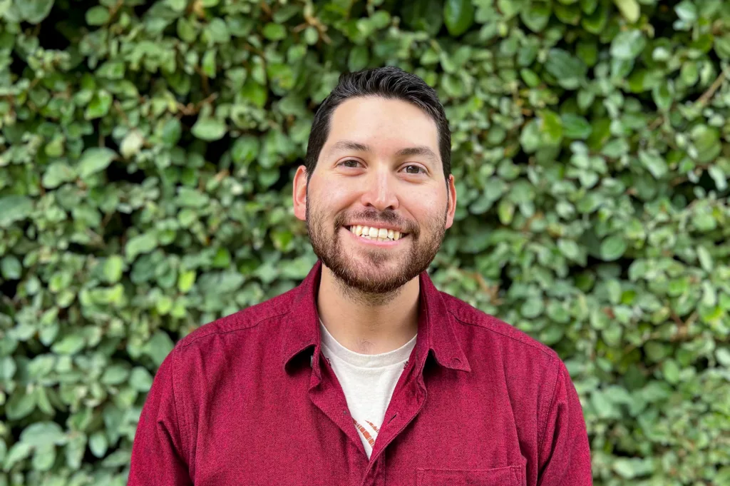 Geo-Launchpad intern Sebastian Griego headshot in front of green foliage.