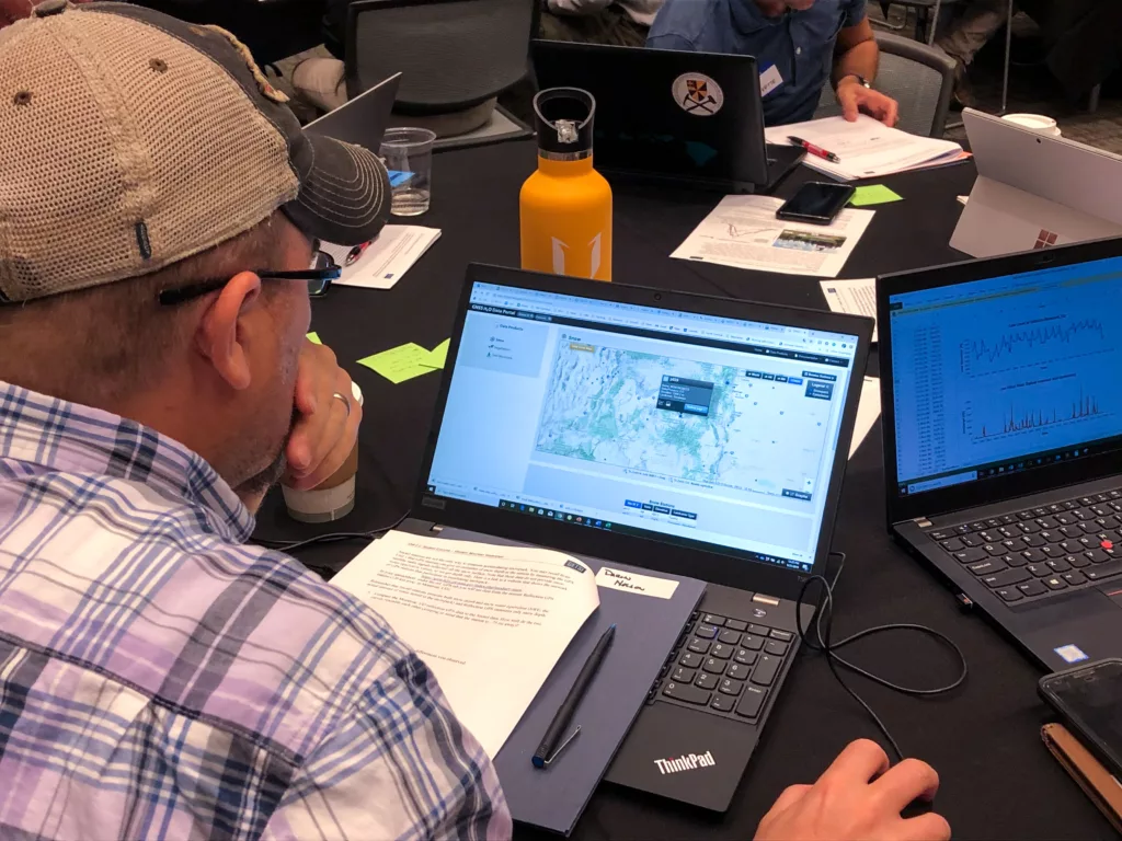 photo over the shoulder of a man working with mapping software on a laptop