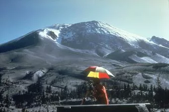 Image of Mount St. Helens and the slope bulge in the background. Observer with bright umbrella in the foreground.
