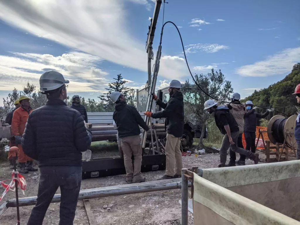 a crew lines up a strainmeter over an open borehole