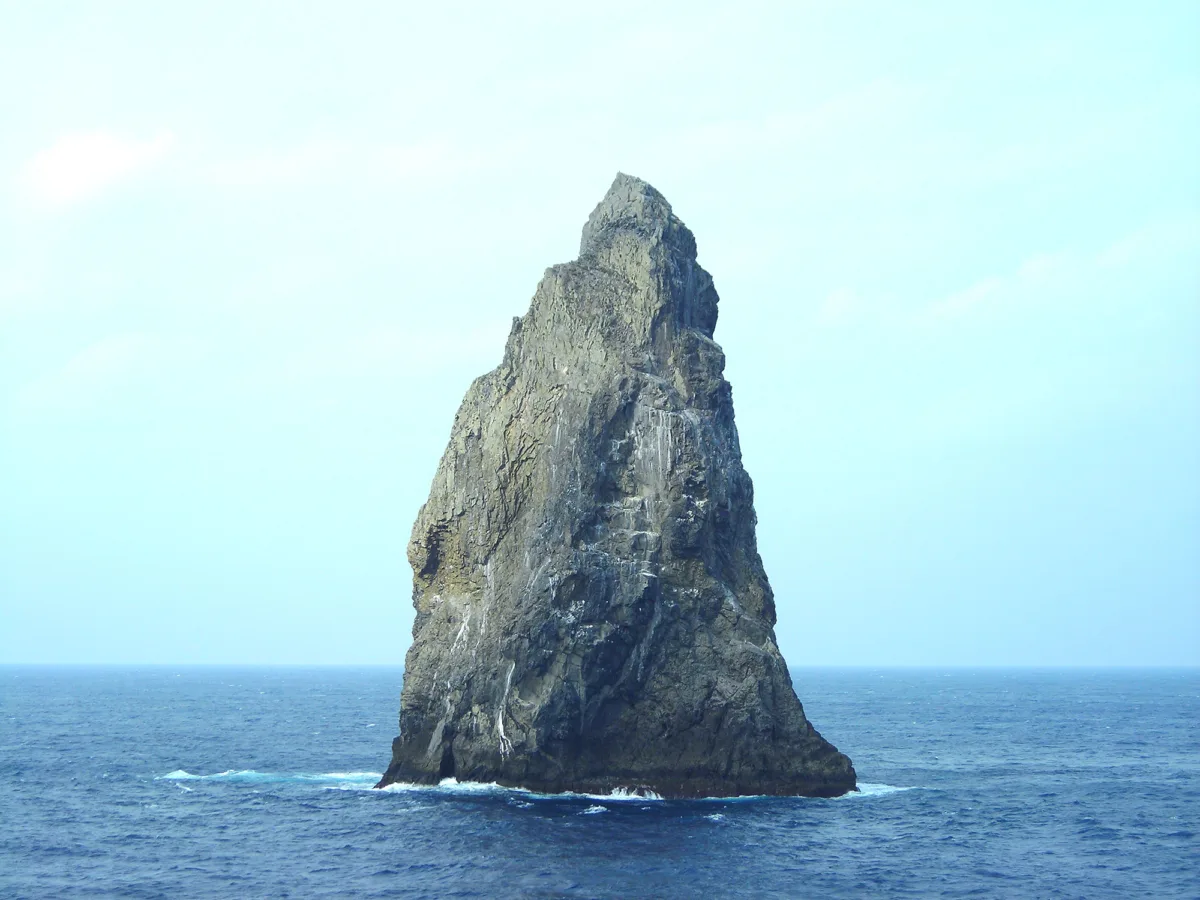 Photo of a tall, steep rock island jutting out of the sea.
