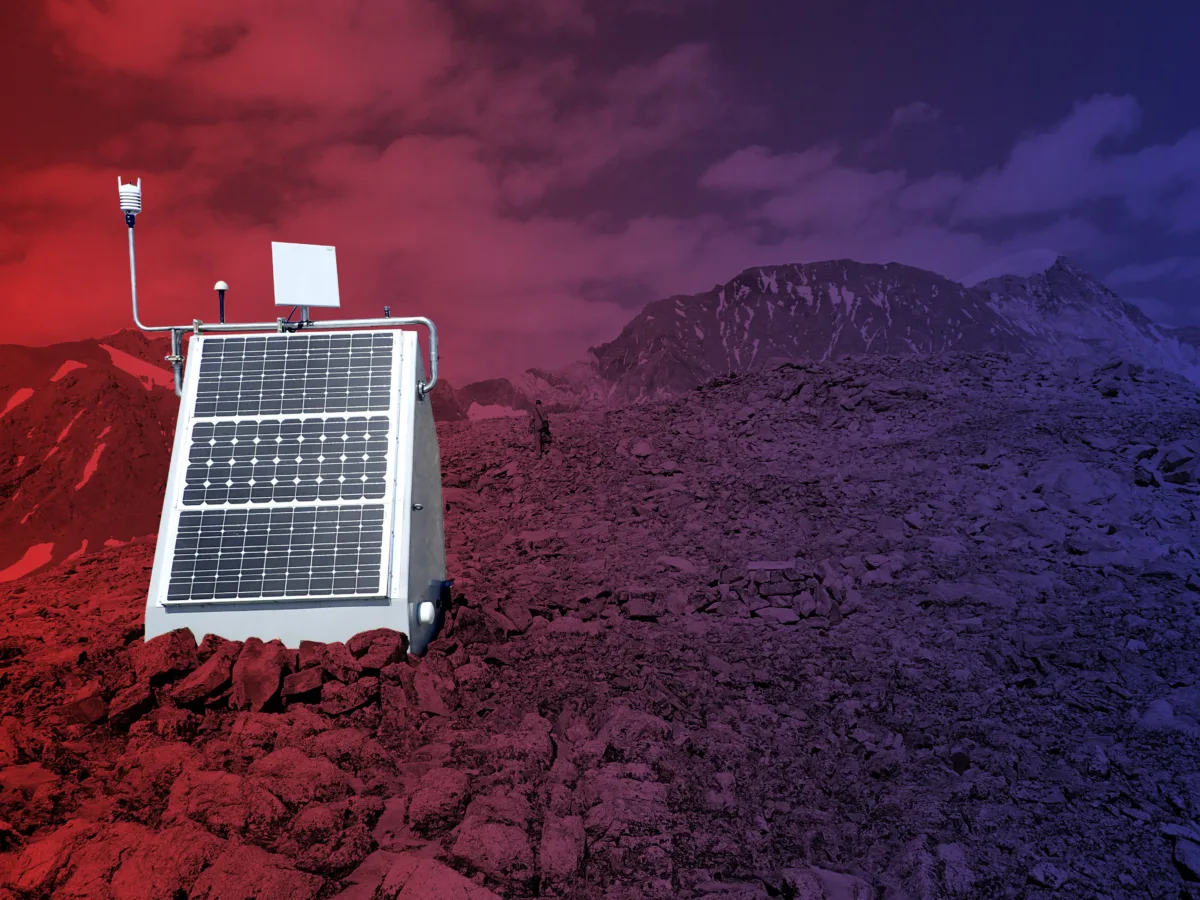 Photo of seismic station enclosure in foreground and a snowy ridge in the distance.