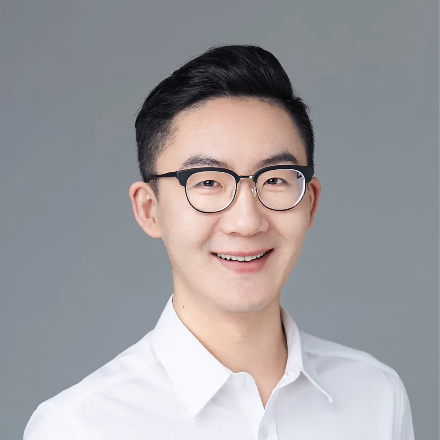 Photo of person with short dark hair and glasses wearing a white collared shirt.