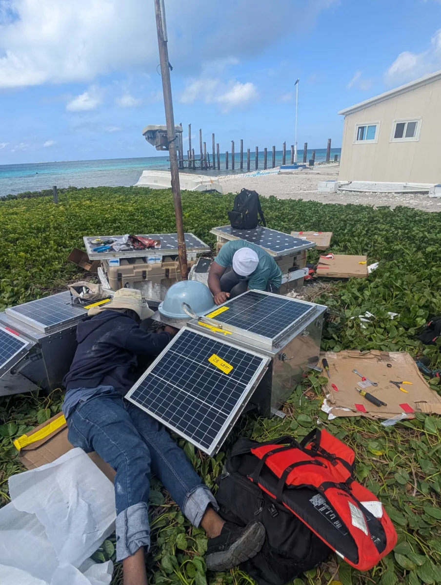 Two people working around station components on the ground.