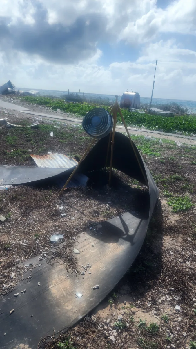 Photo of antenna dangling from monument with a long piece of building material wrapped around it.