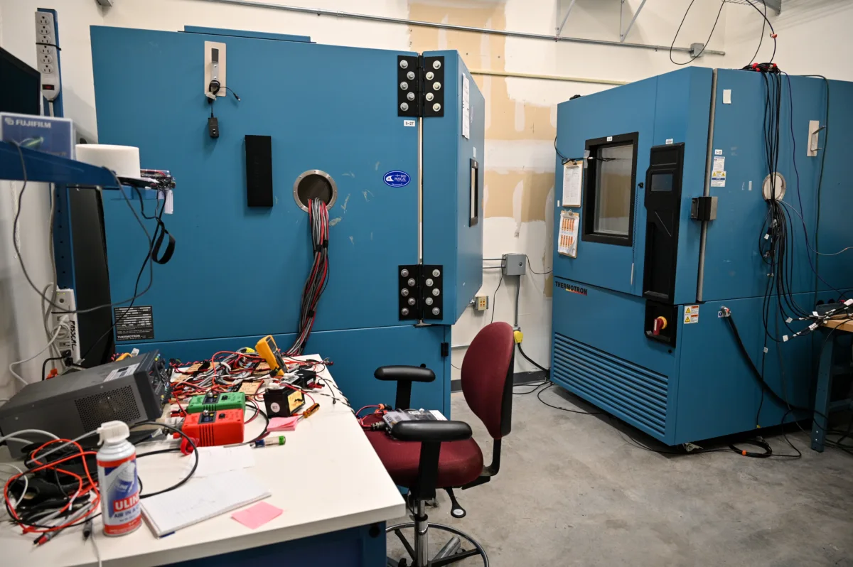 Laboratory room with two large blue test chambers, a desk, and an office chair.