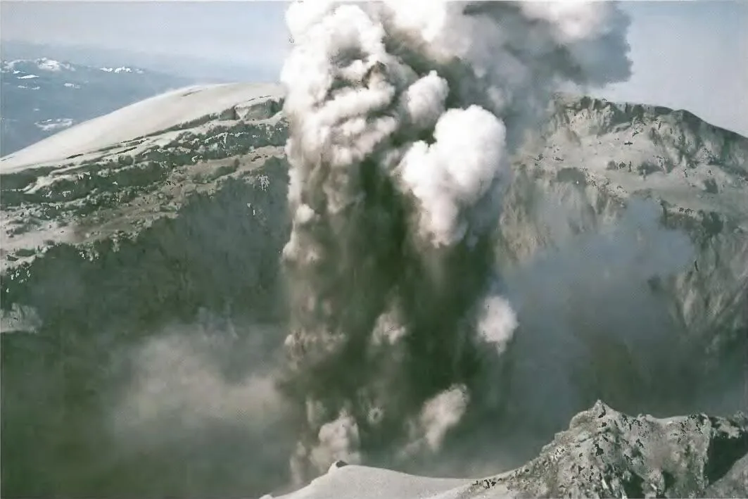Looking into the summit crater of Mount St. Helens, a thick column of steam and ash spouts out. 
