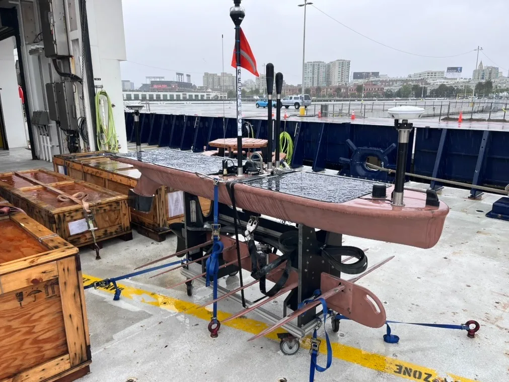 A Wave Glider on the deck of a research vessel with mounted instruments on top. 