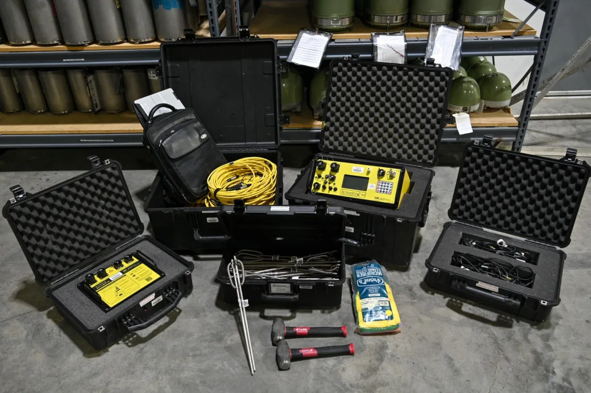 Four black boxes of gear containing ERT equipment in a warehouse.