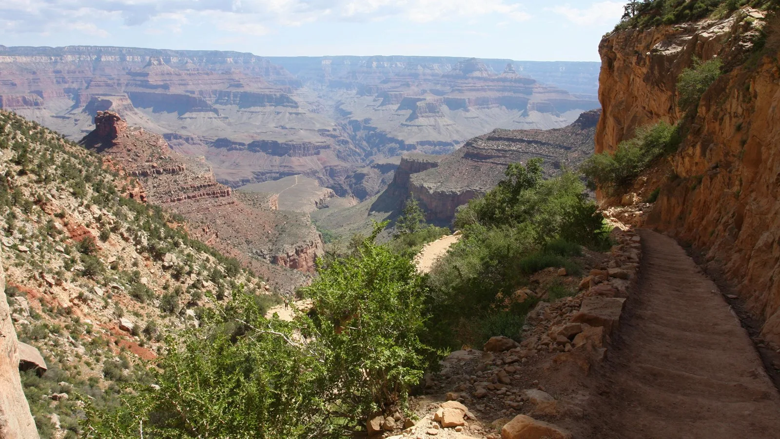 Photo of Bright Angel Trail, with a low stone wall on one size and a cliff face on the other.