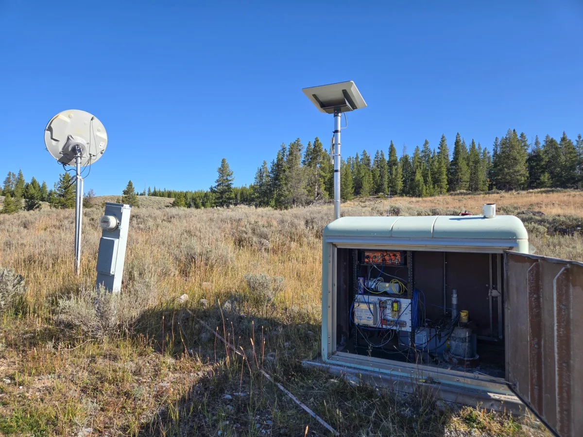 In the foreground, the Panther borehole strainmeter site with the door open revealing the borehole instruments and the computing systems.